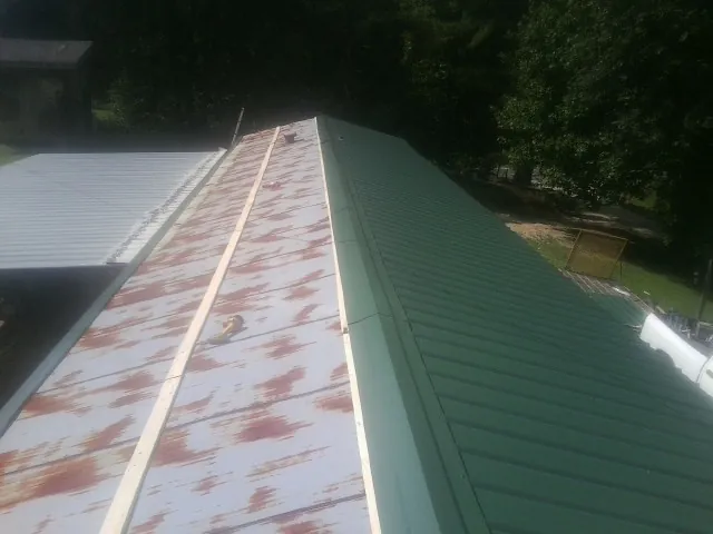 Old rusted panels beside newly installed green metal roofing — Wind Damage Roof Repair by Roofing Brothers in Idaho Springs