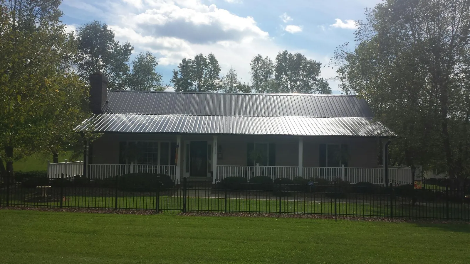 Gray metal roof on a brick ranch with a full width front porch — Gutter Guard Installation work by our crew in Idaho Springs