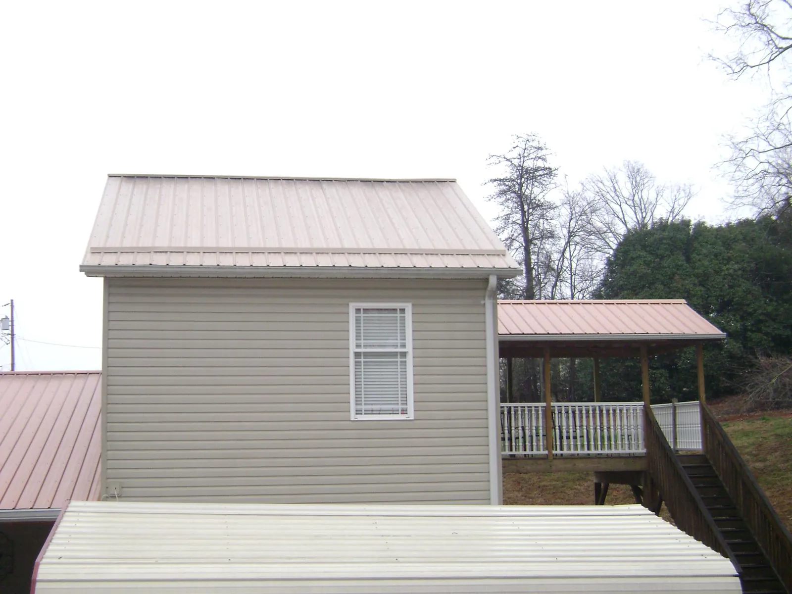 Tan metal roofs on a two story addition and attached porch, from a Roof Replacement job in Idaho Springs