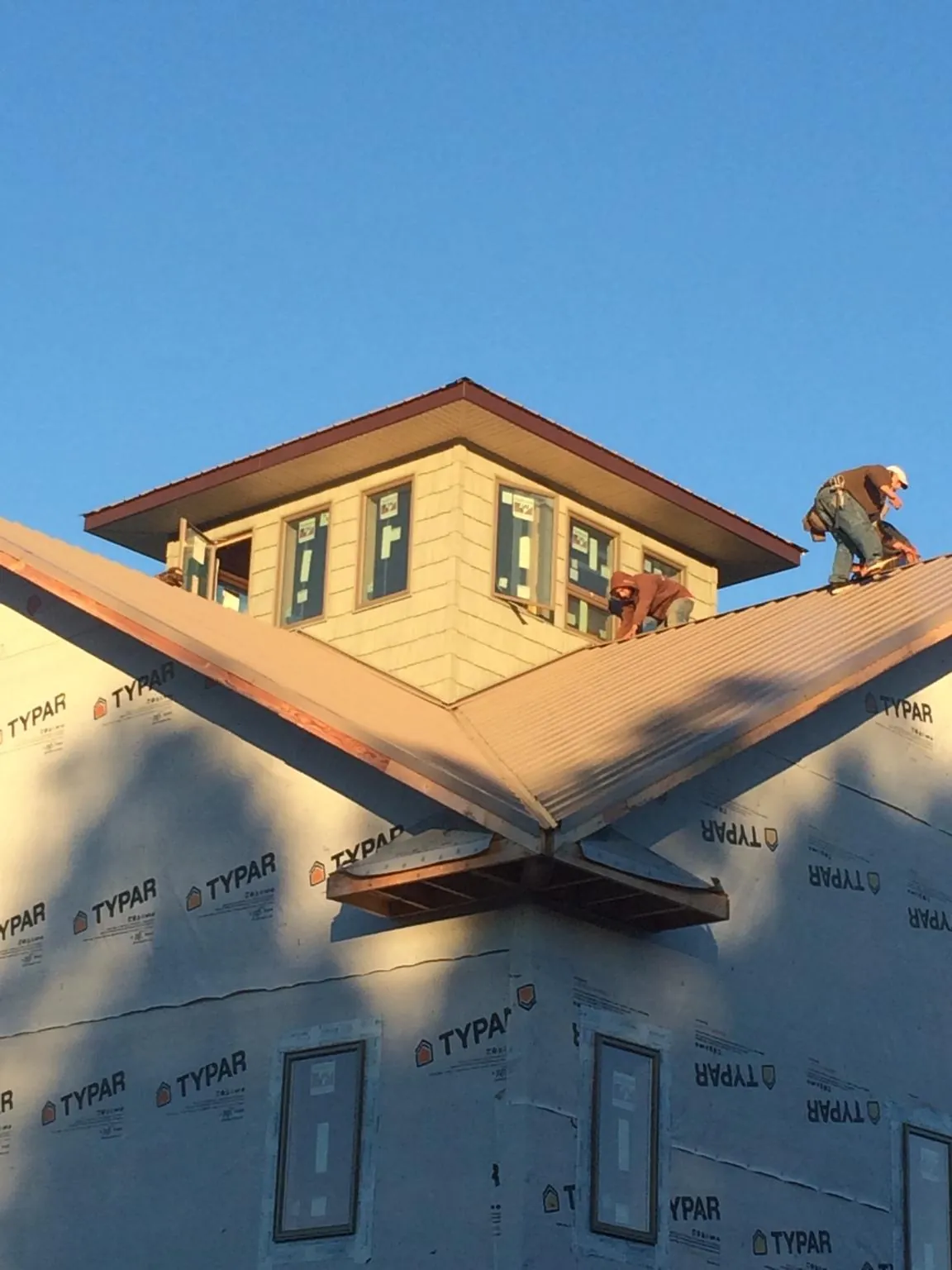 Roofers working around a rooftop cupola on a new metal roof at sunset — Roof Waterproofing in Idaho Springs by Roofing Brothers